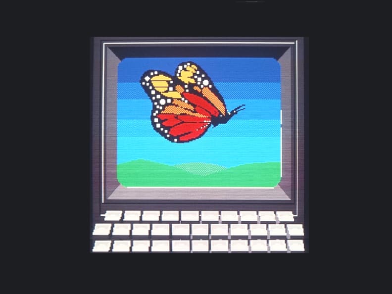 An image drawn using Telidon featuring a computer screen and keyboard. A butterfly is on the computer’s screen.
