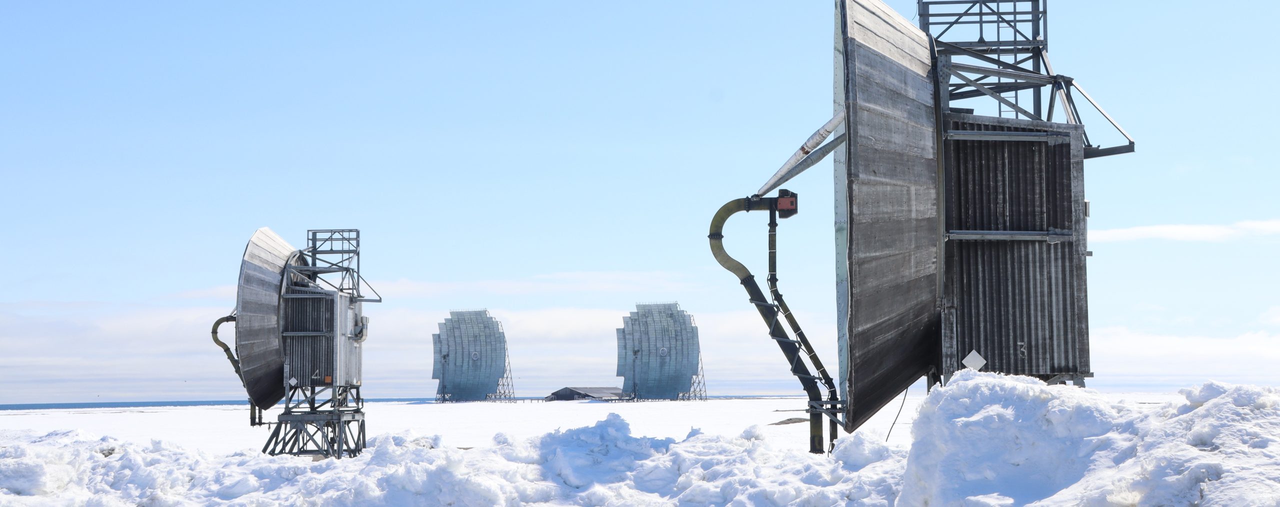 Multiple large grey parabolic antennae set in a snow-covered area.